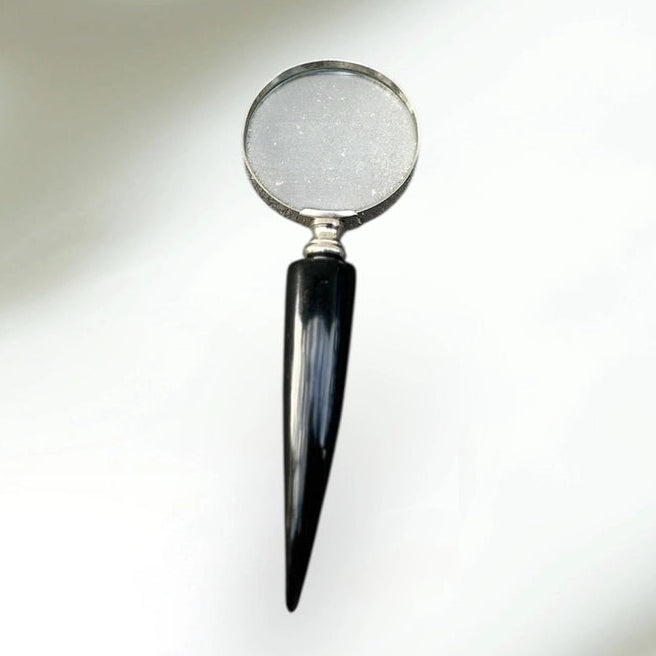 Magnifying glass with a black handle on a reflective surface