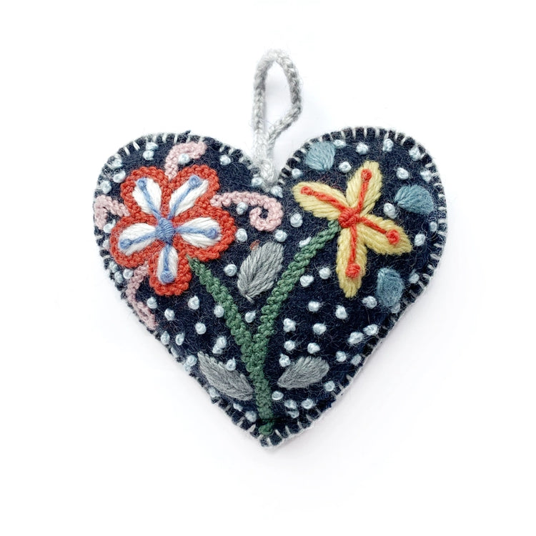 Heart-shaped navy embroidered ornament with floral designs on a white background