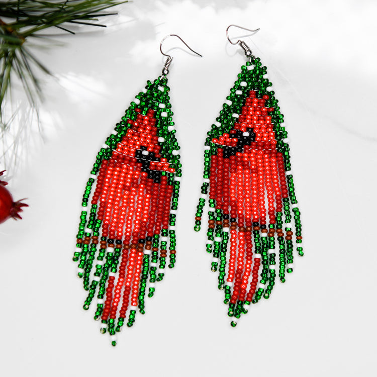 Beaded earrings featuring a large cardinal sitting on a branch against a green background