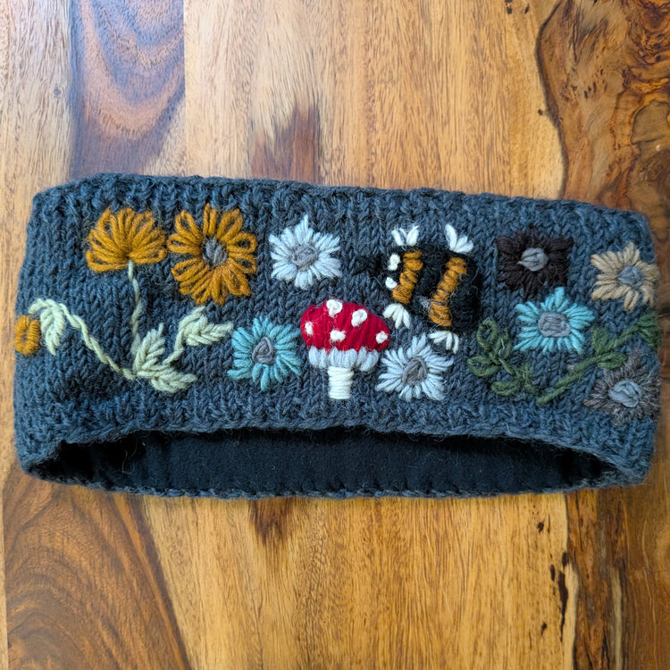 Embroidered wool headband with floral and mushroom designs on a wooden surface