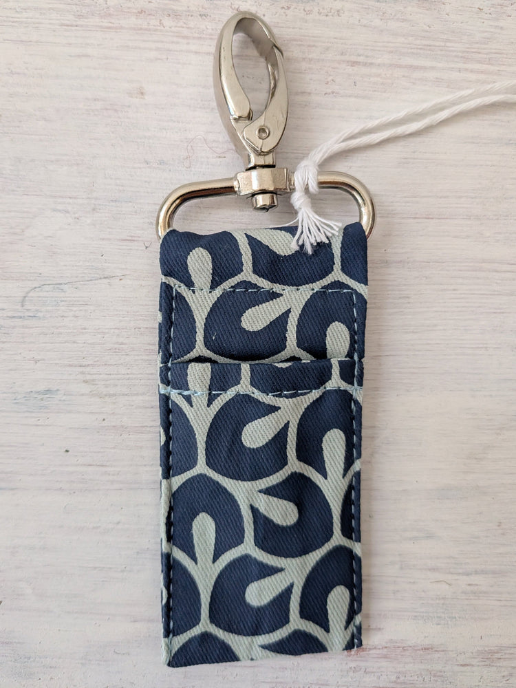 Fabric pouch with keychain clip on a light wooden surface