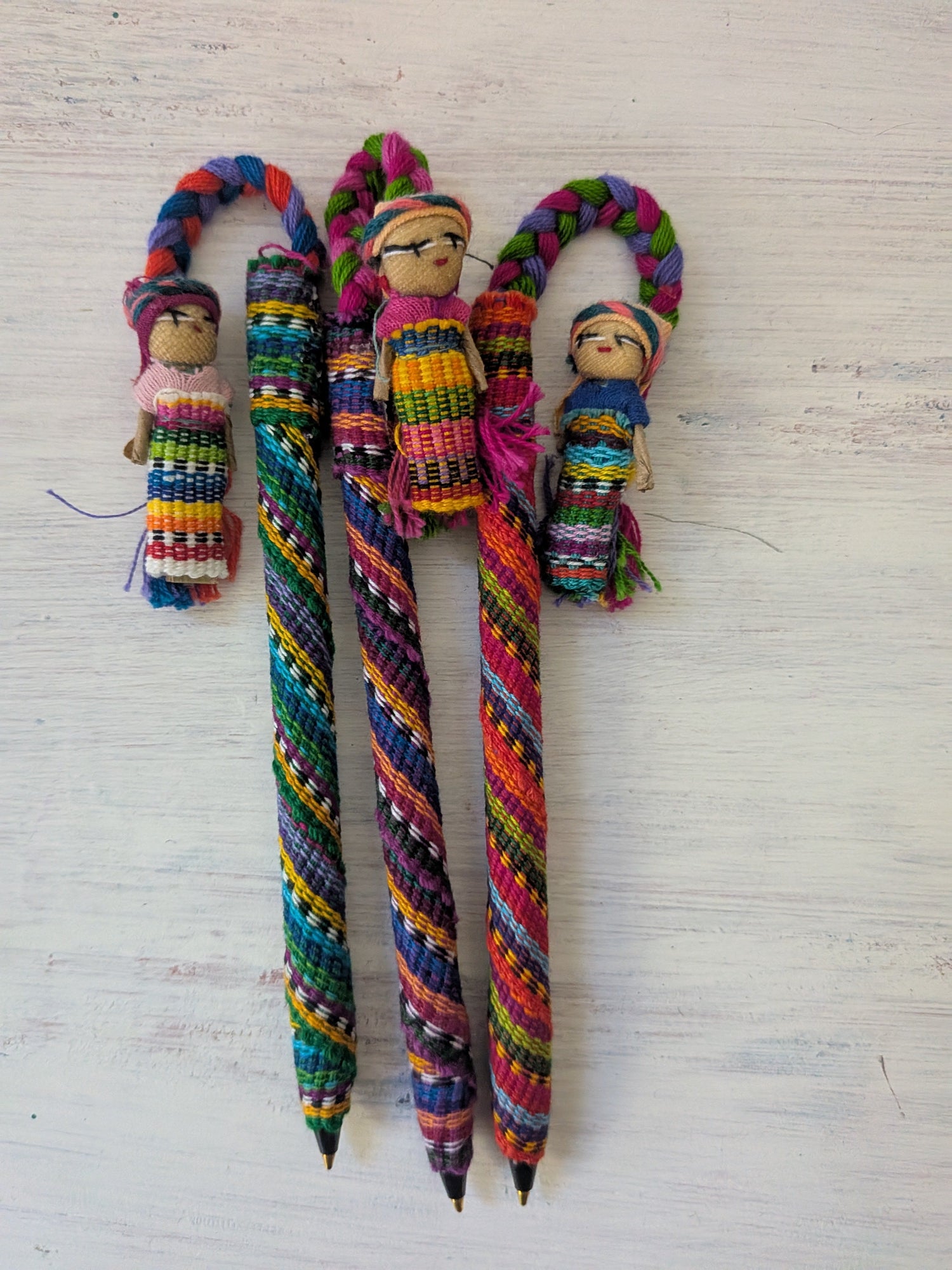 Colorful fabric-covered pens with a handcrafted worry doll attached to the top