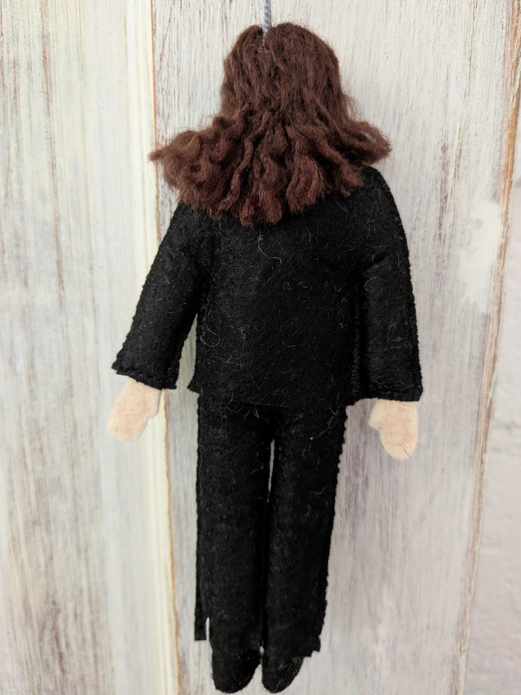 Textile doll with dark hair and black outfit on a wooden background