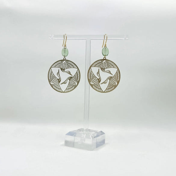 Gold circular earrings with a bird design on a white background