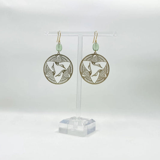 Gold circular earrings with a bird design on a white background