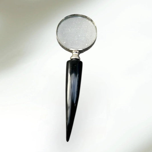 Magnifying glass with a black handle on a reflective surface