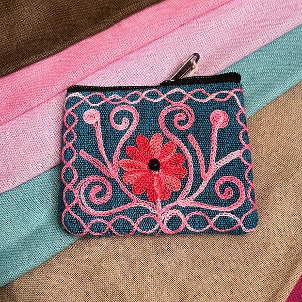 Embroidered coin purse with floral design on a colorful fabric background