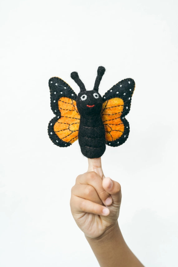 Butterfly-shaped finger puppet held on a finger against a white background
