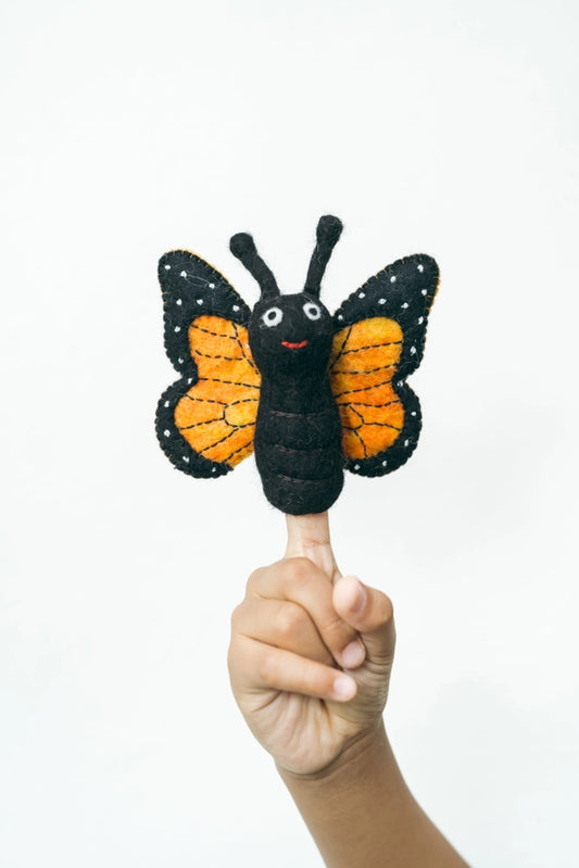 Butterfly-shaped finger puppet held on a finger against a white background