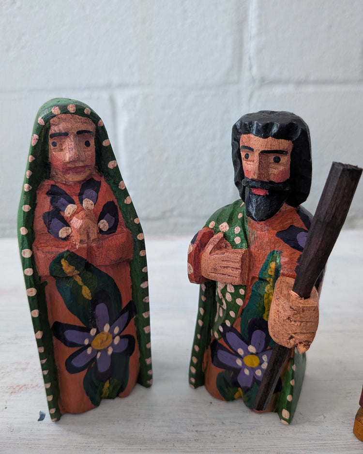 Wooden nativity scene figures of a woman and a man with a staff on a white background