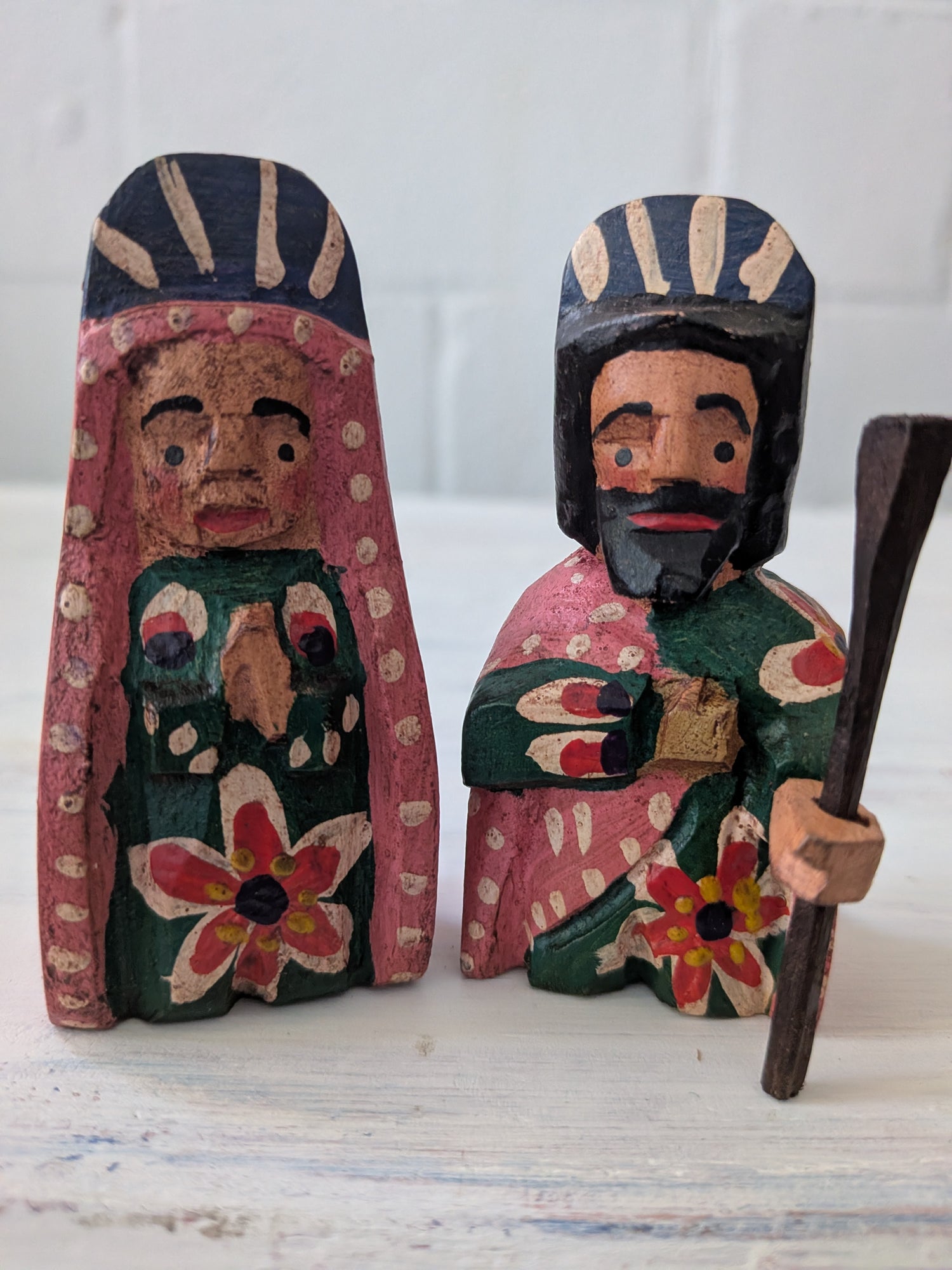 Two wooden nativity figures with colorful patterns on a white background