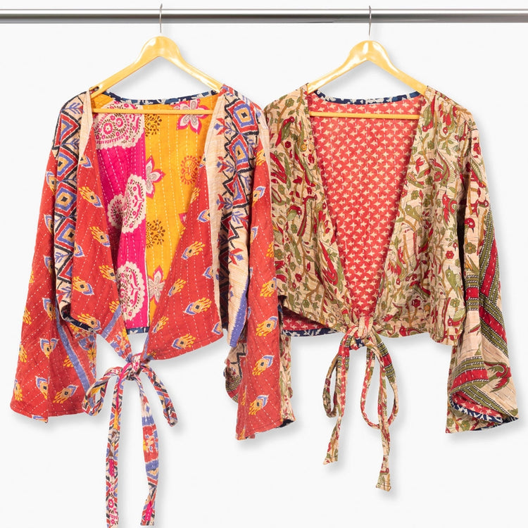 Two colorful patterned tops with bell sleeves hanging on hangers against a white background
