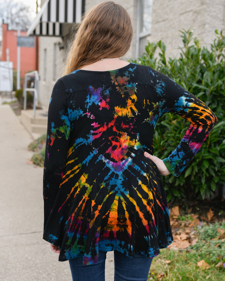Person wearing a tie-dye shirt with colorful patterns outdoors.