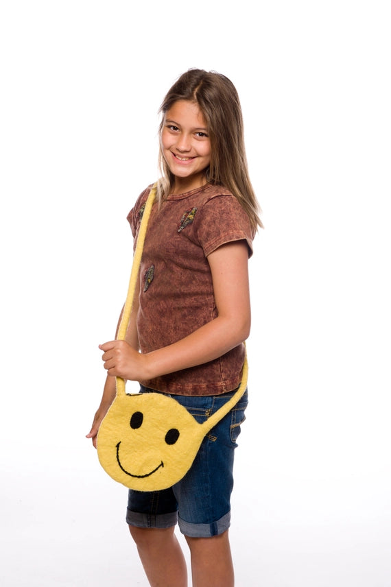 Young girl holding a yellow smiley face bag on a white background