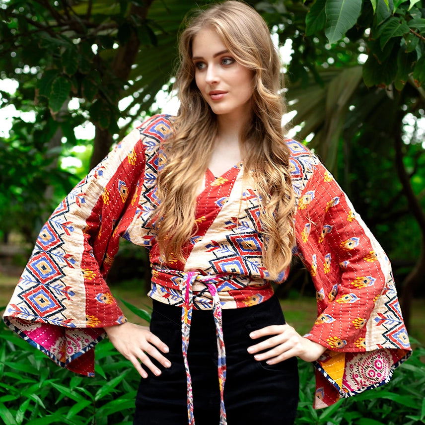 Woman wearing a colorful patterned  top with bell sleeves. Made from Upcycled Kantha fabric.