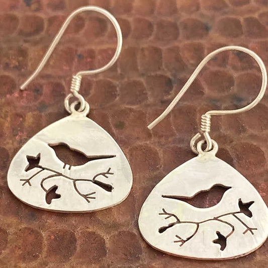 Silver bird and branch earrings on a textured brown background