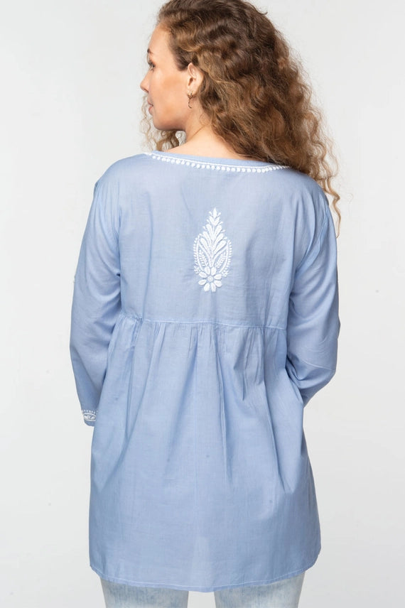 The back of a light blue baby doll tunic with white hand embroidered details 