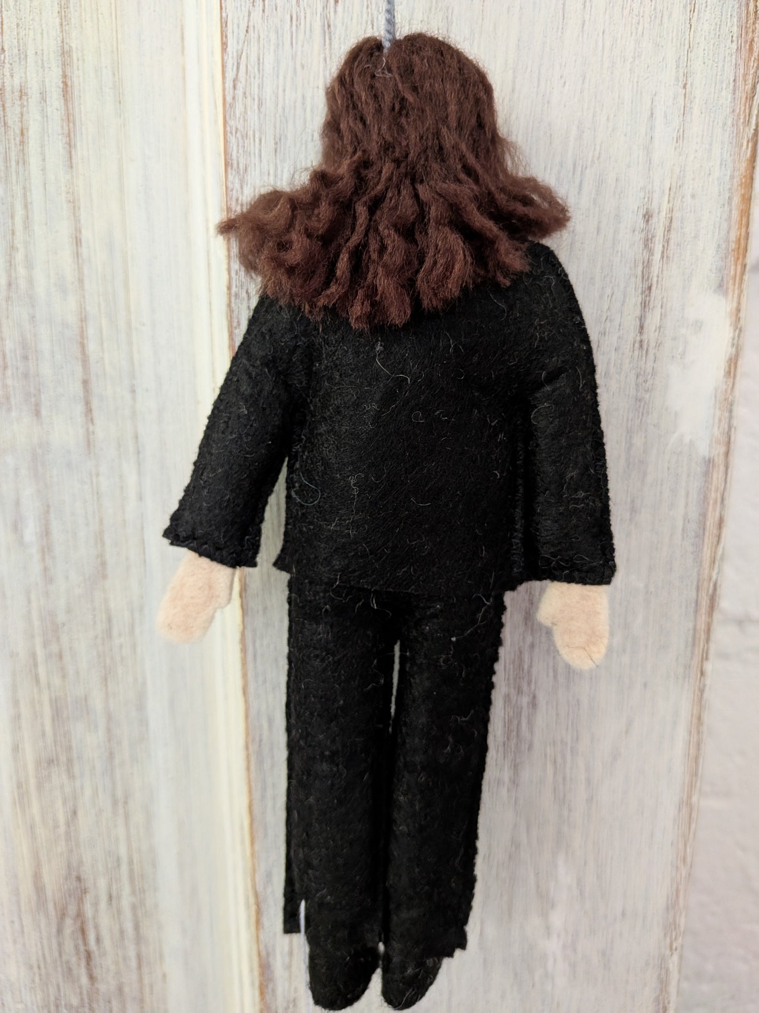 Textile doll with dark hair and black outfit on a wooden background