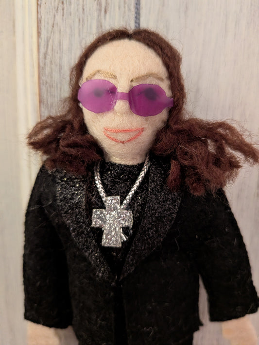 Felt Ozzy Osbourne doll wearing a black outfit with sunglasses and a cross necklace
