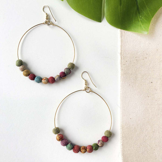 kantha beads on bottom on circle earring thin brass wire. on simple natural background