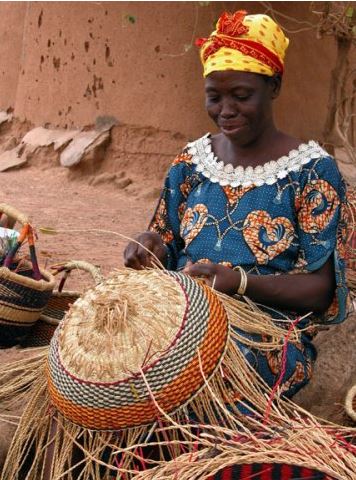 woman weaving a market basket from river grass in Ghana