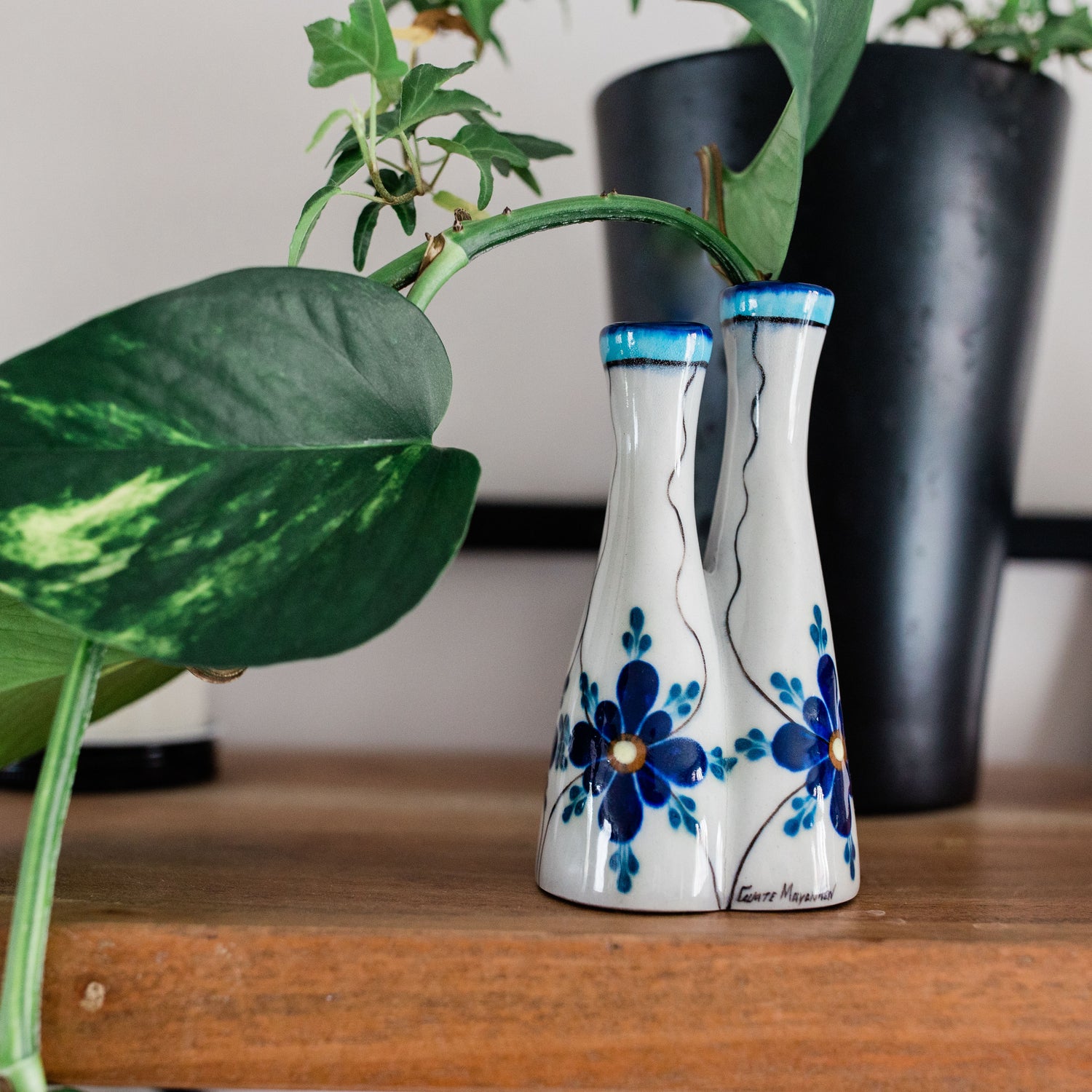blue flowers bud vase in front of potted plant.