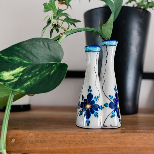blue flowers bud vase in front of potted plant.