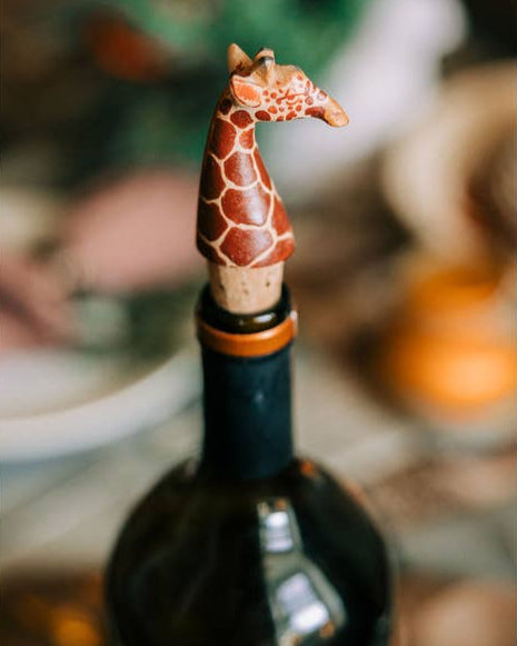 Hand-carved giraffe bottle topper shown being used in a wine bottle