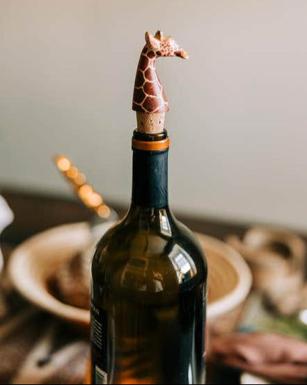 Hand-carved giraffe bottle topper shown being used in a wine bottle