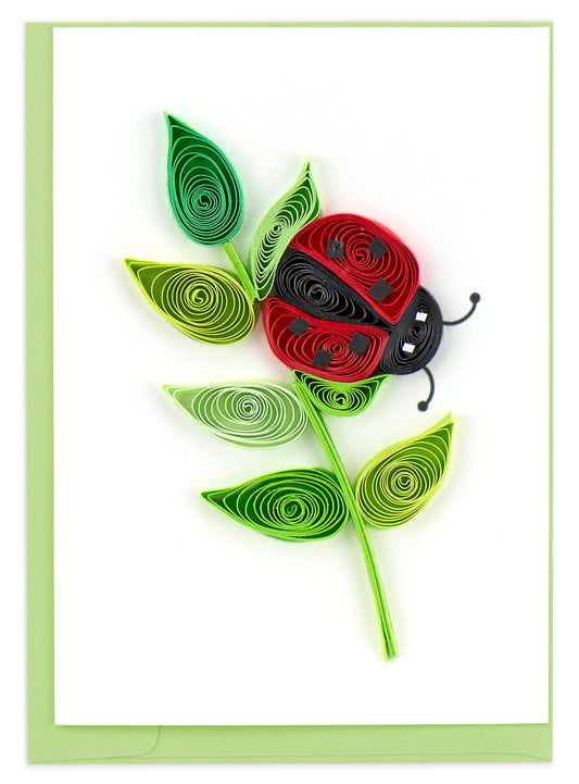 A notecard with a quilled red ladybug design on the front, accompanied by green leaves.