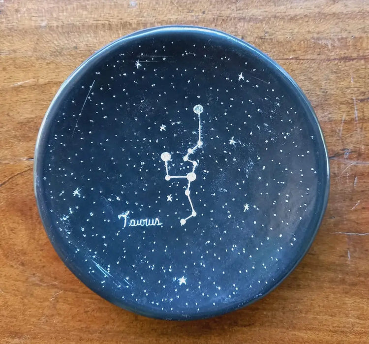 A black ceramic ring dish featuring the Taurus constellation 