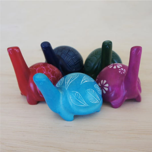 A collection of colorful turtle-shaped stone figurines with etched patterns, displayed on a wooden surface.